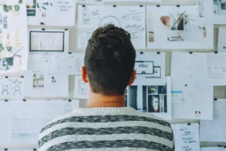 A man looking at the board and applying design thinking process with the printouts of product plans, wireframes, prototypes
