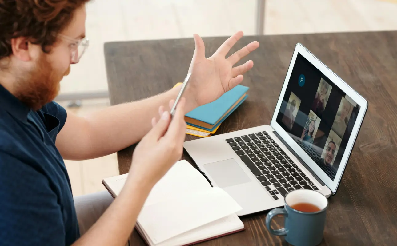 A man having a conference call on his laptop with his team at different remote location