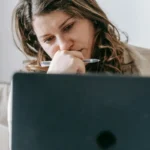 A woman entrepreneur looking at her laptop with a worrying look